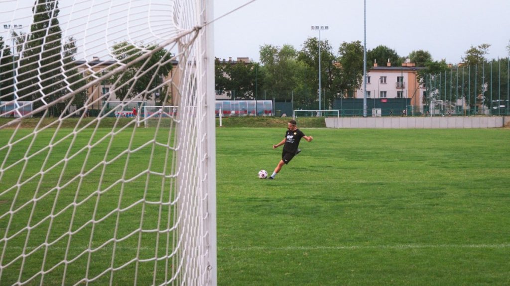A soccer player kicks the ball on a green field