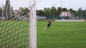 A soccer player kicks the ball on a green field